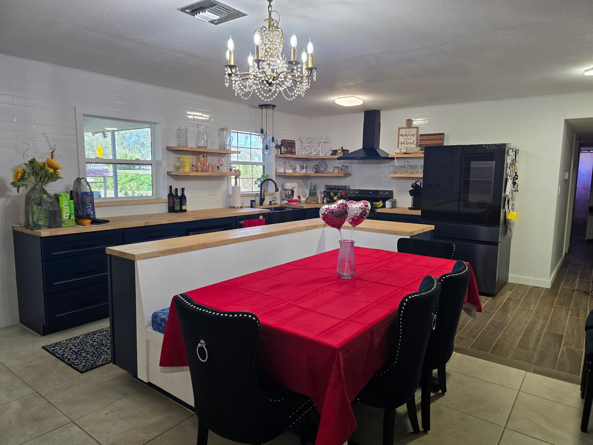 Completed Florida kitchen with navy cabinets, wood countertops, white tile backsplash, open shelving, and built-in seating