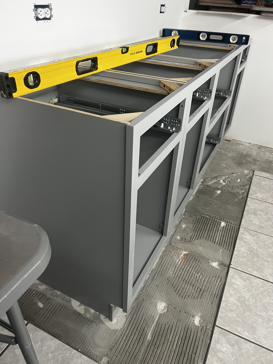 Gray base cabinets being leveled during installation